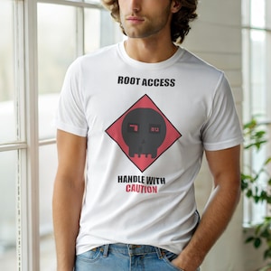 May include: White t-shirt with the text "ROOT ACCESS" above a black skull graphic inside a red diamond. Below the graphic is the text "HANDLE WITH CAUTION". The shirt is short-sleeved.