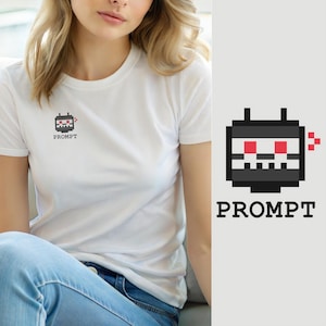 May include: A white short-sleeved t-shirt featuring a small pixel art graphic on the chest. The graphic depicts a black square robot head with two red eyes, a white mouth, and the word PROMPT printed in black capital letters underneath it.