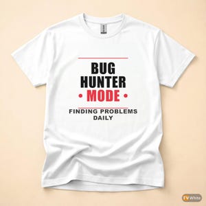 以下が含まれることがあります： 「BUG HUNTER MODE」の文字が黒と赤でプリントされた白いTシャツ。スローガンは「FINDING PROBLEMS DAILY」です。柔らかい素材でできており、クラシックなクルーネックです。