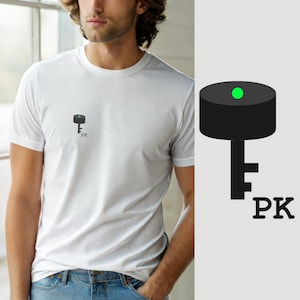 Może przedstawiać: Biały t-shirt z krótkim rękawem z małą grafiką na lewej piersi. Grafika przedstawia czarny cylindryczny kształt z jasnym zielonym punktem na górze, przypominający klucz, umieszczony nad czarnymi wielkimi literami PK.