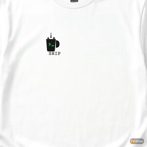 Puede incluir: Camiseta blanca con un gráfico de taza negra y una flecha verde, con la palabra "SHIP" debajo. La taza tiene tres puntos encima, sugiriendo vapor. El diseño está centrado en el pecho.