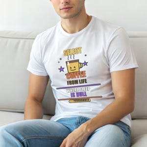 May include: White t-shirt with a colorful graphic design. The design features a smiling coffee cup, stars, and the text "SELECT COFFEE FROM LIFE WHERE SLEEP IS NULL --PROGRAMMER". The shirt is worn by a person wearing blue jeans.