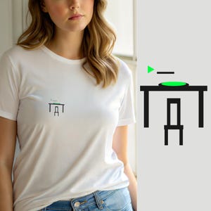 Peut inclure: Un t-shirt blanc à manches courtes avec un petit motif centré sur la poitrine. Le graphique représente une table et une chaise en lignes noires avec un accent circulaire vert vif sur le plateau et une petite icône triangulaire verte.