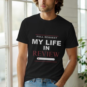 Puede incluir: Camiseta negra de cuello redondo con el texto "PULL REQUEST MY LIFE IN REVIEW" en blanco y rojo. La camiseta presenta un gráfico de barra de progreso. La camiseta la lleva una persona.
