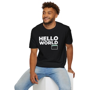 Peut inclure: T-shirt noir avec l'inscription blanche "HELLO WORLD" et un petit graphique d'écran d'ordinateur. Le t-shirt est de style col rond.