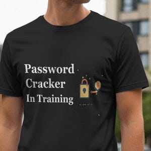 May include: Black t-shirt with the text "Password Cracker In Training" in white. The design includes a gold padlock and key graphic. The shirt is made of a soft material.