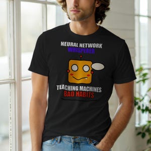 Op de afbeelding: Zwart t-shirt met de tekst "NEURAL NETWORK WHISPERER" boven een cartoonrobot met de tekst "TEACHING MACHINES BAD HABITS". De robot is geel met twee ogen, een mond en een tekstballon.