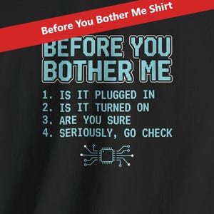 Pode incluir: Camiseta preta com o texto "BEFORE YOU BOTHER ME" em azul claro. Abaixo, quatro etapas de solução de problemas e um gráfico de placa de circuito. Uma faixa vermelha no topo diz "Before You Bother Me Shirt".