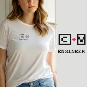 Op de afbeelding: Een wit T-shirt met korte mouwen en een kleine afbeelding op de linkerborst. De afbeelding bestaat uit een zwart vierkant met de letter C, een rood plusteken en een zwarte rechthoek met de letter U, met daaronder het woord ENGINEER.