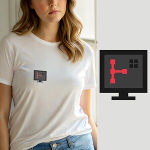 Puede incluir: Una camiseta blanca de manga corta con un pequeño gráfico en el pecho. El gráfico muestra un icono de monitor de ordenador negro que contiene una forma geométrica roja que se asemeja a una T estilizada y una pequeña cuadrícula negra.