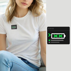 Op de afbeelding: Een wit T-shirt met korte mouwen en een kleine zwarte rechthoekige afbeelding op de borst. De afbeelding toont een terminalvenster-pictogram met een groen batterijsymbool met twee X-tekens, samen met twee regels groene codetekst eronder.