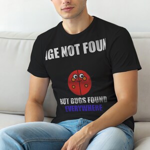 May include: Black t-shirt with the text "IMAGE NOT FOUND" above a cartoon ladybug graphic. Below the ladybug, the text reads "BUT BUGS FOUND EVERYWHERE". The ladybug is red with black spots and a smiling face.