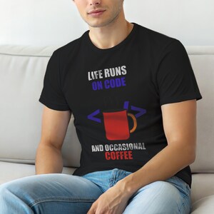 Puede incluir: Camiseta negra con el texto "LIFE RUNS ON CODE" en blanco y azul, y "AND OCCASIONAL COFFEE" en rojo. Una taza de café roja con vapor en el centro, con símbolos de código a ambos lados.