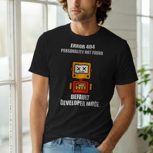 May include: Black t-shirt with a robot graphic and the text "ERROR 404 PERSONALITY NOT FOUND" and "DEFAULT DEVELOPER MODE". The robot is yellow and red with a white box and black "XX" eyes.