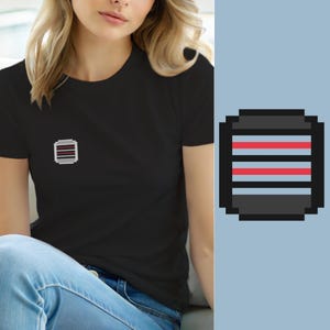 May include: A black short-sleeved t-shirt featuring a small pixel art graphic on the left chest. The graphic is a square icon with a dark grey border, containing two horizontal red stripes separated by a thin grey line against a dark background.
