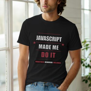 Könnte beinhalten: Schwarzes T-Shirt mit dem Text "JAVASCRIPT MADE ME DO IT" in Weiß und Rot. Das Shirt enthält auch den Satz "UNDEFINED BEHAVIOR INCLUDED" in Rot. Das Design hat zwei rote Sterne.