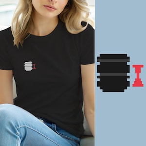May include: A black short-sleeved t-shirt featuring a small pixel art graphic on the left chest. The graphic consists of a grey, multi-layered cylindrical shape positioned next to a smaller, red, vertically oriented hourglass-like pixelated icon.