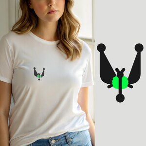 Könnte beinhalten: Ein weißes kurzärmeliges T-Shirt mit einer kleinen, zentrierten Grafik auf der Brust. Die Grafik besteht aus einem leuchtend grünen Kreis, der hinter einer schwarzen, symmetrischen abstrakten Form platziert ist, die einem Insekt ähnelt.