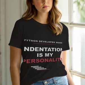 Puede incluir: Camiseta negra con texto blanco que dice "PYTHON DEVELOPER MODE" y "INDENTATION IS MY PERSONALITY". El texto está en negrita, sin serifa. La camiseta tiene cuello redondo y mangas cortas.