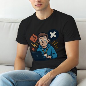 Könnte beinhalten: Schwarzes T-Shirt mit einer Cartoon-Illustration einer traurigen Person mit einem Laptop, einer Sprechblase mit einem X und anderen technischen Symbolen. Die Person trägt einen blauen Kapuzenpullover und ein Namensschild.