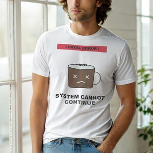 May include: White t-shirt with a humorous design. The shirt features a brown coffee mug with an unhappy face, the word "NULL", and the text "SYSTEM CANNOT CONTINUE" below a red banner that reads "! FATAL ERROR !".