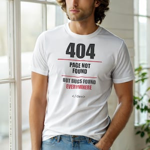 May include: White t-shirt with the text "404 Page Not Found But Bugs Found Everywhere" in black and red. The shirt also includes the text "</dev>". The t-shirt is a crew neck and short-sleeved.