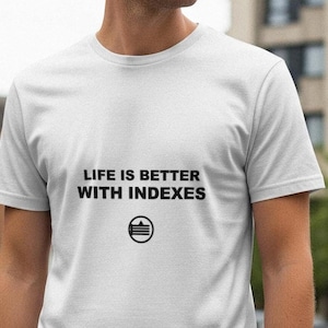 May include: White t-shirt with the text "LIFE IS BETTER WITH INDEXES" in black, along with a circular graphic. The shirt is short-sleeved and appears to be made of a soft material. The person wearing the shirt is standing outside.