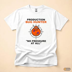 Può includere: T-shirt bianca con la scritta "PRODUCTION BUG HUNTER" in nero e arancione. Sotto, un disegno di insetto dei cartoni animati all'interno di un bersaglio e la frase "NO PRESSURE AT ALL" è stampata sotto.