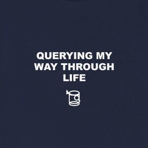 Może przedstawiać: Granatowa koszulka z białym napisem "QUERYING MY WAY THROUGH LIFE". Pod tekstem znajduje się biała grafika kubka. Koszulka wykonana jest z miękkiego materiału.
