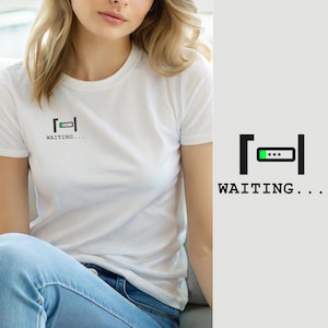 Könnte beinhalten: Ein weißes T-Shirt mit kurzen Ärmeln und einer kleinen Grafik auf der linken Brustseite. Die Grafik zeigt ein schwarzes Ladebalken-Symbol mit einem grünen Fortschrittssegment und dem darunter gedruckten Text "WAITING..." in schwarzer Schrift.