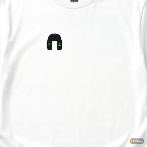 Op de afbeelding: Wit T-shirt met een zwarte afbeelding van een headset met groene accenten. De headsetafbeelding heeft een groene pijl naar rechts en een groen dubbele punt-symbool. Het shirt is gemaakt van zwaar katoen.