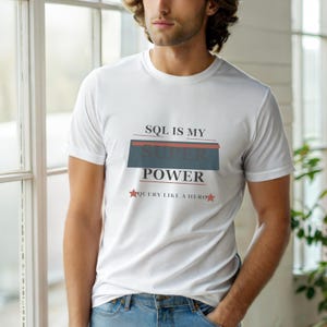 May include: A white short-sleeved t-shirt featuring the text SQL IS MY SUPER POWER in black and dark gray, with a dark gray rectangular block behind the word SUPER and the text QUERY LIKE A HERO below, accented by two small red stars.
