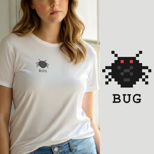 Op de afbeelding: Een wit T-shirt met korte mouwen en een kleine, zwarte, gepixelde insectafbeelding op de linkerborst. De afbeelding toont een gestileerde kever met twee rode ogen en het woord "BUG" eronder gedrukt in een eenvoudig, zwart, schreefloos lettertype.