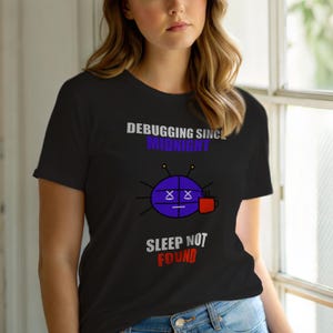 Puede incluir: Camiseta negra con el texto "DEBUGGING SINCE MIDNIGHT" sobre un gráfico azul con ojos tachados y una taza de café. Debajo del gráfico, el texto dice "SLEEP NOT FOUND".