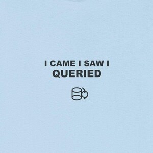 May include: Pale blue t-shirt featuring the black text "I CAME I SAW I QUERIED" and a database symbol graphic. The shirt is made of a soft fabric and has short sleeves.