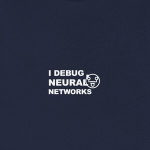 May include: Navy blue t-shirt with the text "I DEBUG NEURAL NETWORKS" in white, along with a stylized graphic. The shirt is made of a soft material and has short sleeves. A casual garment for everyday wear.