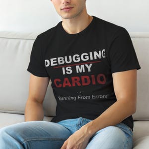 May include: Black t-shirt with the text "DEBUGGING IS MY CARDIO" in white and red. Below the text is the phrase "Running From Errors". The shirt is a crew neck and is being worn.