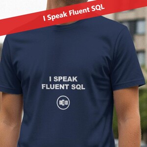 Może przedstawiać: Granatowa koszulka z białym napisem "I Speak Fluent SQL". Koszulka posiada grafikę ikony głośnika pod tekstem. Czerwony baner z napisem "I Speak Fluent SQL" znajduje się powyżej.