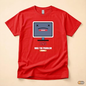 Op de afbeelding: Rood t-shirt met een afbeelding van een computermonitor met een foutmelding. De monitor heeft een verdrietig gezicht en de tekst "DNS WAS THE PROBLEM again" staat eronder. Het shirt is gemaakt van een zacht materiaal.