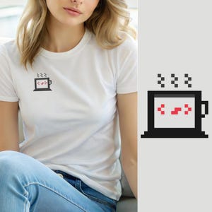 Peut inclure: Un t-shirt blanc à manches courtes avec un petit motif en pixel art sur la poitrine. Le motif représente une tasse de café noire avec de la vapeur qui s'en échappe et des crochets de code rouges à l'intérieur, évoquant la programmation.