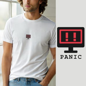 Op de afbeelding: Een wit T-shirt met korte mouwen en een kleine afbeelding op de borst. De afbeelding toont een zwart computermonitor-icoon met een rood scherm met twee rode uitroeptekens, met daaronder het woord PANIC in zwarte letters gedrukt.