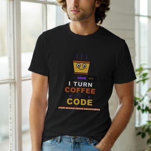 Op de afbeelding: Zwart t-shirt met een afbeelding van een lachende koffiekop en de tekst "I TURN COFFEE INTO CODE AND BUGS INTO FEATURES". Het ontwerp bevat paarse, oranje en gele kleuren. Het t-shirt wordt door een persoon gedragen.