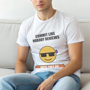 Op de afbeelding: Wit T-shirt met de tekst "COMMIT LIKE NOBODY REVIEWS" boven een gele emoji met zonnebril en een paarse zweetdruppel. Daaronder staat de tekst "UNTIL THEY DO" in oranje.