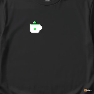 Peut inclure: T-shirt noir avec un motif de tasse blanche et des détails verts. La tasse a un dessus vert et un motif vert sur le devant. Le t-shirt est en coton épais.