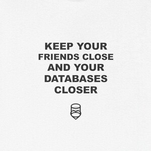 May include: White t-shirt with black text: "KEEP YOUR FRIENDS CLOSE AND YOUR DATABASES CLOSER." A small graphic of two stacked cylinders is below the text. The shirt is made of a soft, lightweight material.