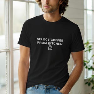 Może przedstawiać: Czarny t-shirt z okrągłym dekoltem z białym napisem "SELECT COFFEE FROM KITCHEN" i grafiką filiżanki do kawy. Koszulka wykonana jest z miękkiego materiału.