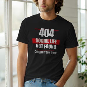 May include: Black crew neck t-shirt with the text "404 SOCIAL LIFE NOT FOUND CODING TOOK OVER" in white and red. The shirt is worn by a person in blue jeans.