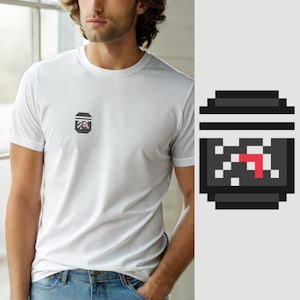 May include: A white short-sleeved t-shirt featuring a small pixel art graphic on the left chest. The graphic depicts a dark gray container with a black lid, containing white pixelated shapes and a single red pixelated arrow pointing to the right.