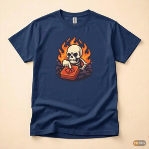 Könnte beinhalten: Marineblaues T-Shirt mit einem Cartoon-Skelett-Motiv. Das Skelett ist von Flammen umgeben und drückt einen roten Knopf. Das Design hat einen Cartoon-Stil.