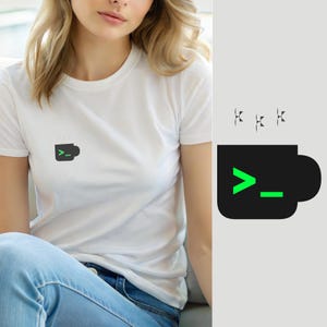 Puede incluir: Una camiseta blanca de manga corta con un pequeño gráfico en el pecho. El gráfico muestra un icono de taza de café negra con un símbolo de línea de comandos verde brillante que consiste en un signo de mayor que y un guion bajo dentro.